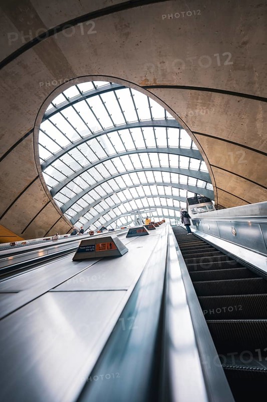 Modern escalator in a futuristic building with arched glass roof and concrete walls, Canary Wharf Station, London, United Kingdom
