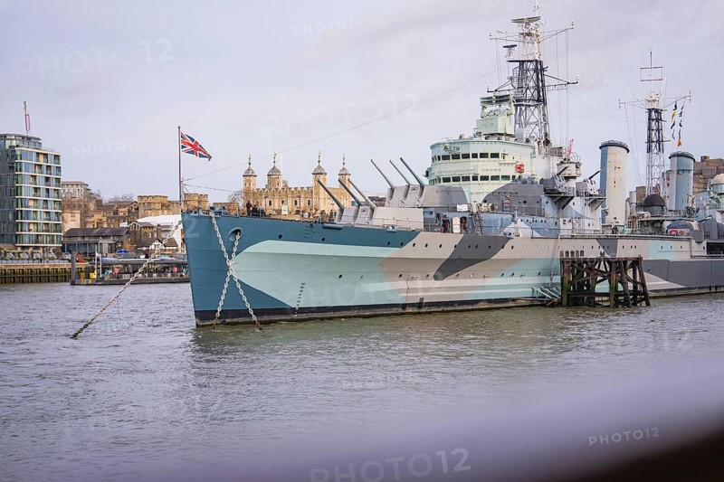 Historic warship on the riverbank in a city with British flag and buildings in the background, HMS Belfast, London, United Kingdom