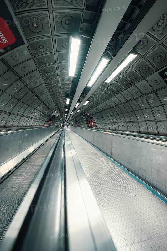 A subway tunnel with escalator and futuristic atmosphere through lighting and architecture, London, United Kingdom