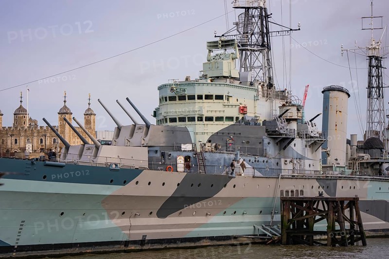 Detailed view of a historic warship with guns, towers in the background, HMS Belfast, London, United Kingdom