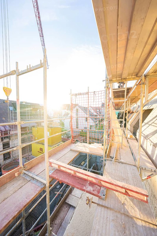 View from above of a construction site with scaffolding at sunset. Urban environment visible, carpentry construction site, roof extension, renovation, Stuttgart, Germany