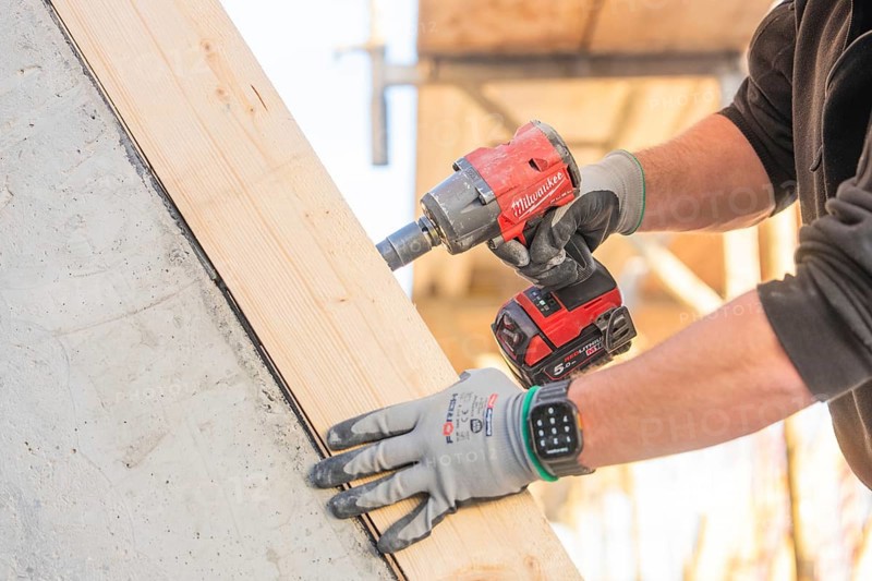 A worker with a cordless screwdriver fixing a piece of wood on a construction site, carpentry construction, roof removal, renovation, Stuttgart, Germany