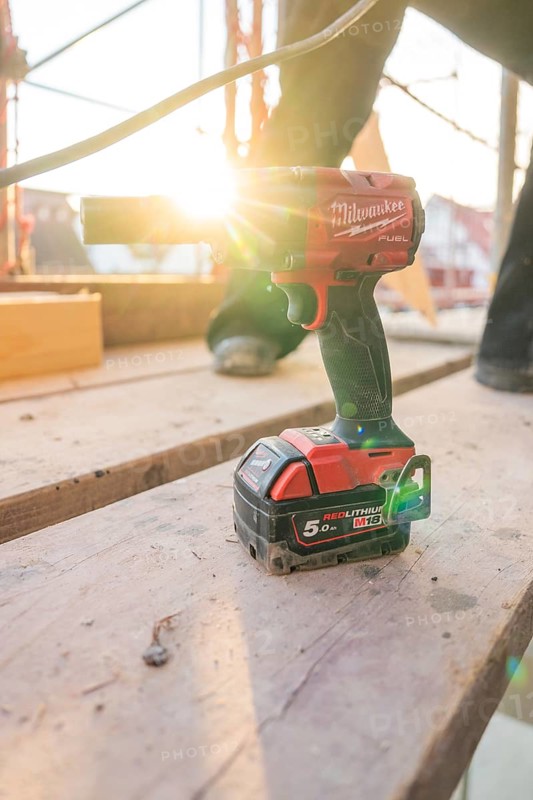 A cordless screwdriver is lying on wooden scaffolding, illuminated by the evening sun, carpentry construction, roof extension, renovation, Stuttgart, Germany