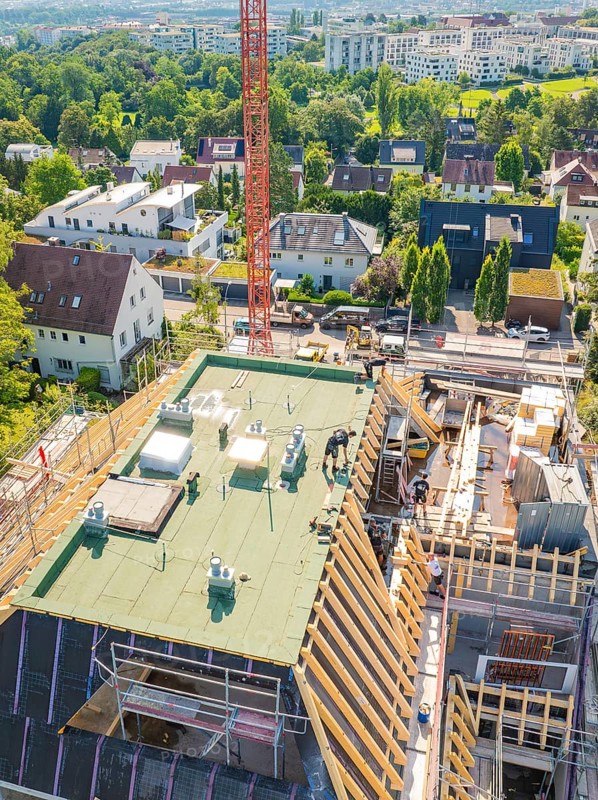 Top view of a building with a crane in an urban environment with lots of greenery, carpentry construction, roof extension, renovation, Stuttgart, Germany