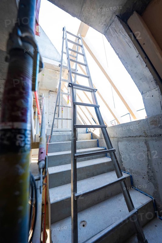 A steel staircase leads to a ladder under a concrete opening that leads upwards, carpentry construction, roof extension, renovation, Stuttgart, Germany