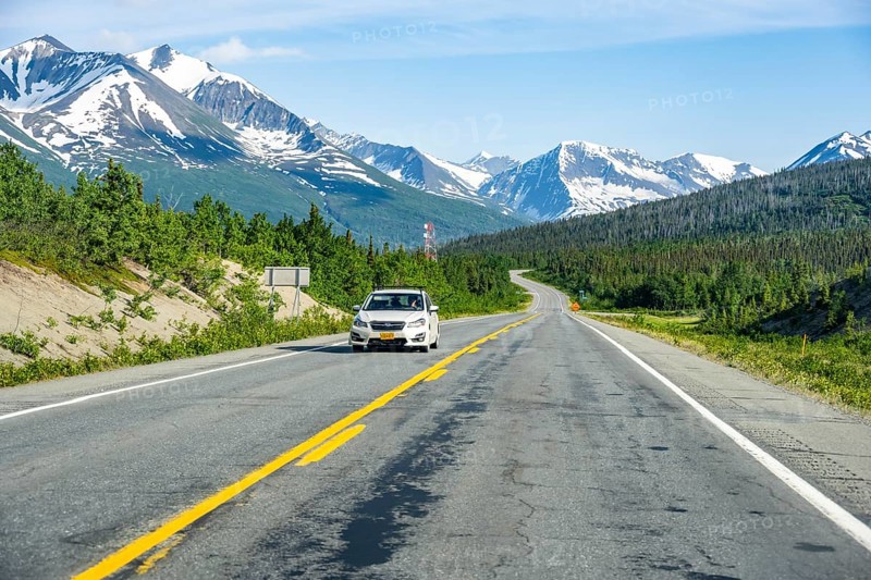 Car on road through taiga and mountainous landscape, picturesque landscape on Richardson Highway, Alaska, USA