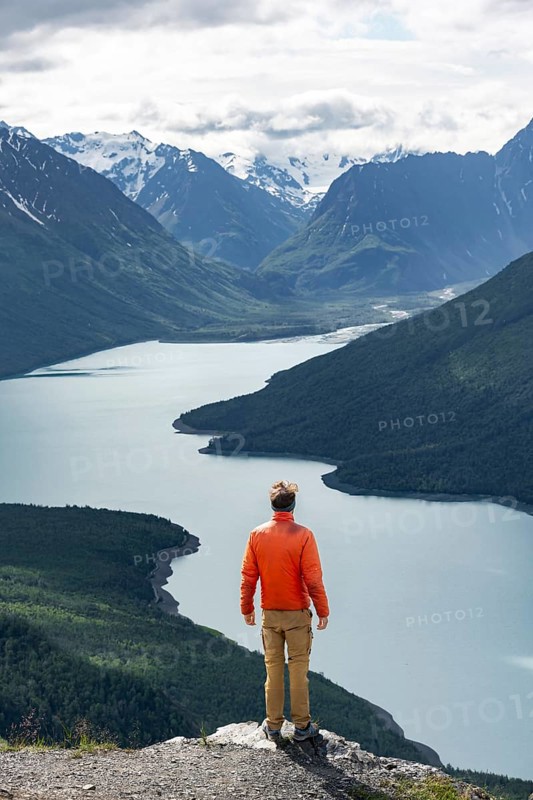 Mountaineer enjoys views of blue lake and mountains on Twin Peaks Trail, Eklutna Lake, Chugach Mountains, Chugach State Park, Alaska, USA