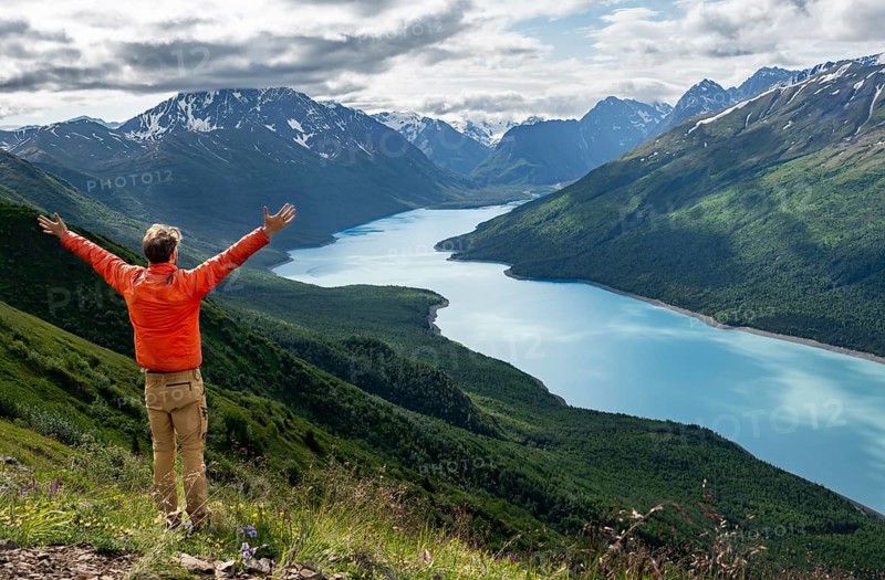 Mountaineer stretches arms in the air, enjoys views of blue seas and mountains on Twin Peaks Trail, Eklutna Lake, Chugach Mountains, Chugach State Park, Alaska, USA