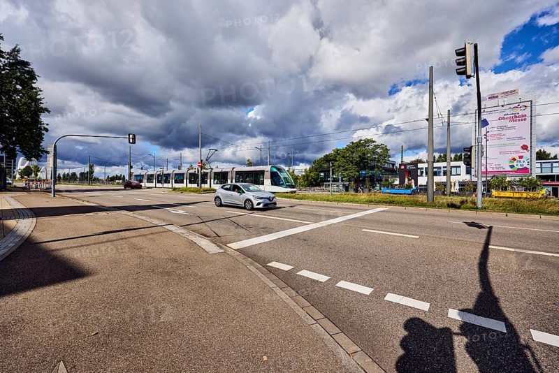 Tram, cars, street, sidewalk, lanes, cycle path, catenary masts, overhead line, central island, trees, meadow, blue sky, cumulus clouds, cumulus congestus clouds, confluence of main street in Strassburger Straße, Kehl, Upper Rhine Valley, Ortenau district, Baden-Württemberg, Germany