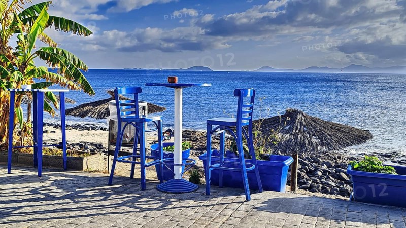 View of the sea from a terrace with blue chairs. A relaxed, sunny coastal scene, Playa Blanca Lanzarote