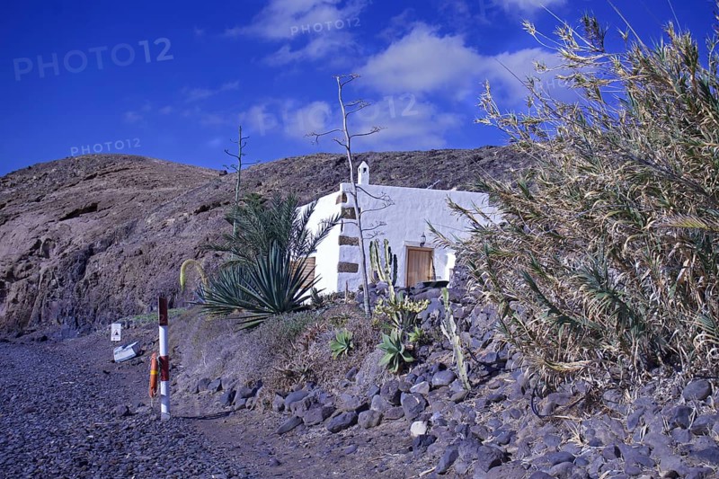 Lonely house in a barren volcanic landscape under a clear blue sky, Playa Quemada, Yaiza Lanzarote