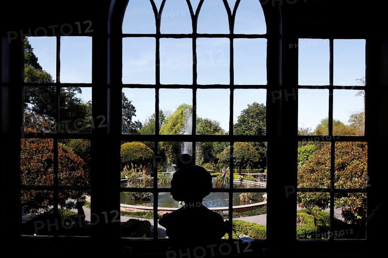 View through a window of a well-kept garden with a bust in the foreground, zero