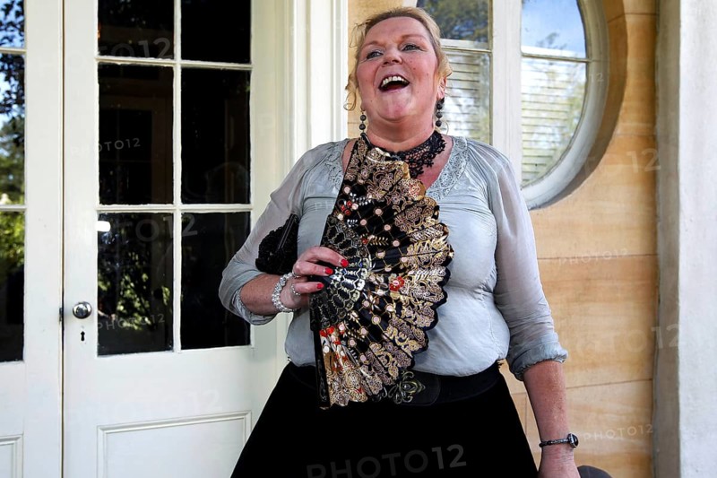 Laughing woman with decorative fan standing in front of an elegant entrance, Houmas House, Louisiana, USA