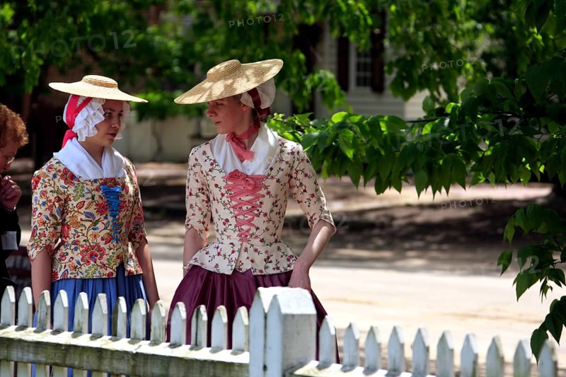 Women in period costumes with hats walking along Duke of Gloucester Street, Williamsburg, Virginia, USA