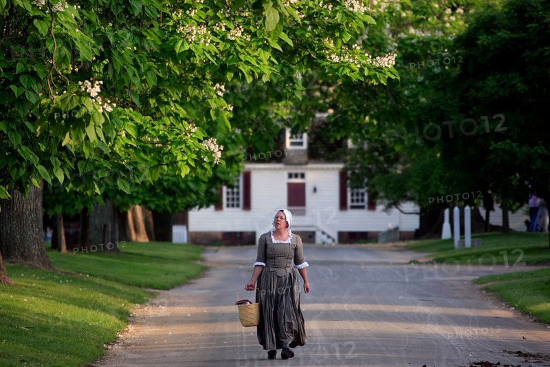 Woman wearing historical costume on a tree-lined street in Colonial Williamsburg, Williamsburg, Virginia, USA