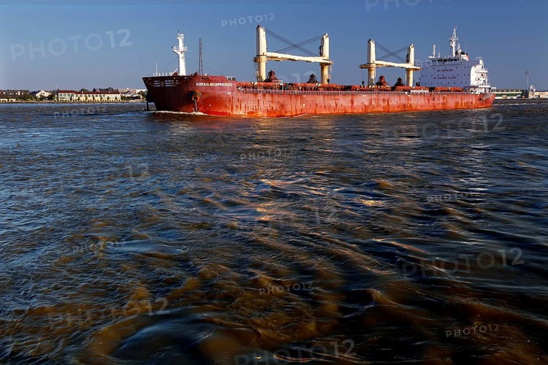 Cargo ship on a river with reflecting water and blue sky, New Orleans, Louisiana, USA