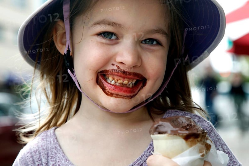 Happy girl with chocolate ice cream on her face smiles at the camera. Wears a summer hat, Savannah, Georgia, USA