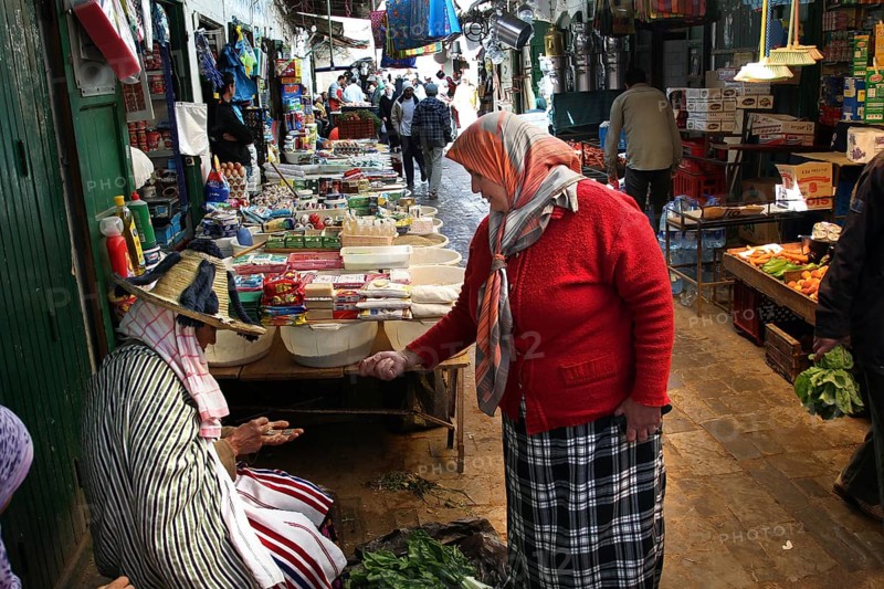 Two woman in traditional clothing talking at a busy market, Tetouan, Medina, Morocco
