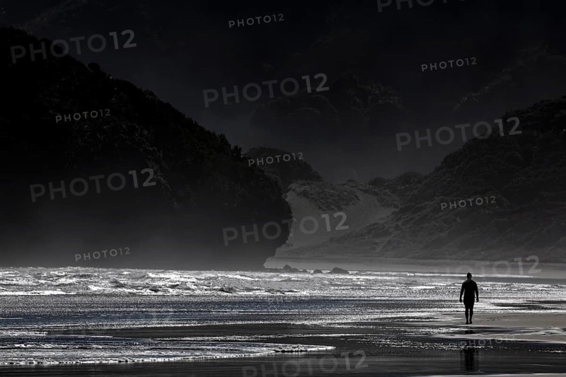 Person walking along the dramatic coastline of Bethells Beach, Te Henga, region, New Zealand