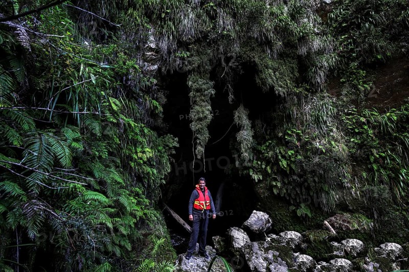 A person in a cave in the green, moss-covered forest near the Whanganui River on a canoe trip, zero