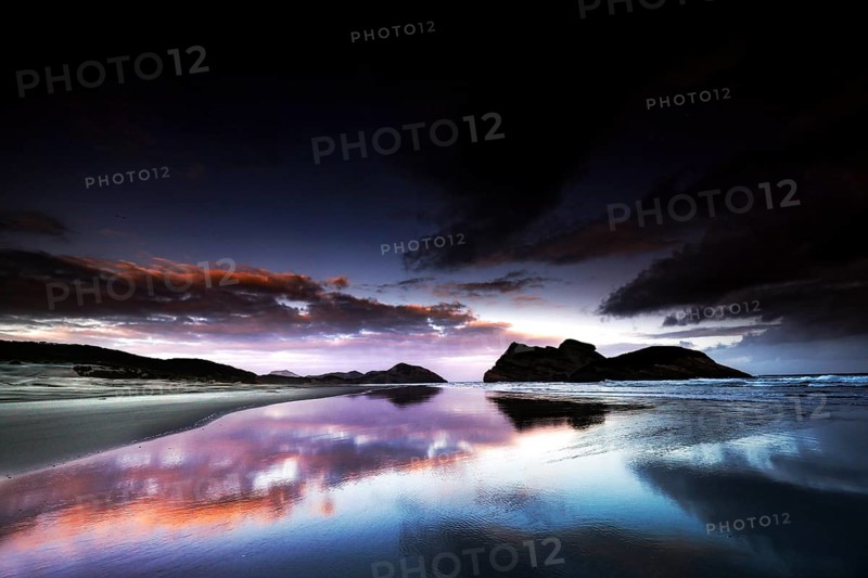 Dramatic sunset on Wharariki Beach with impressive reflection in the water, Wharariki, Tasman, New Zealand
