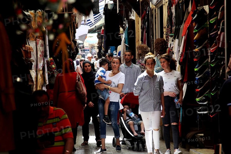 People stroll through a narrow market alley with traditional shops, Fez, Fez el Bali, Morocco