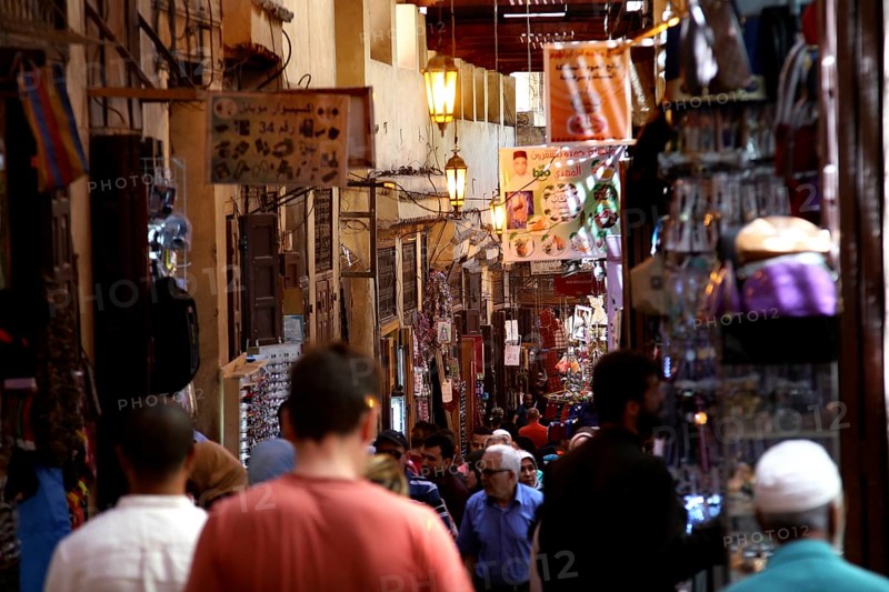 Lively market activity in a narrow, colorful alley with many visitors, Fez, Fez el Bali, Morocco