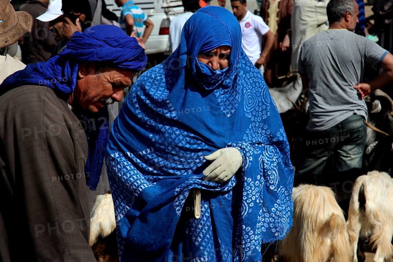 Man and woman in blue robes at a cattle market with goats, Guelmim, Morocco