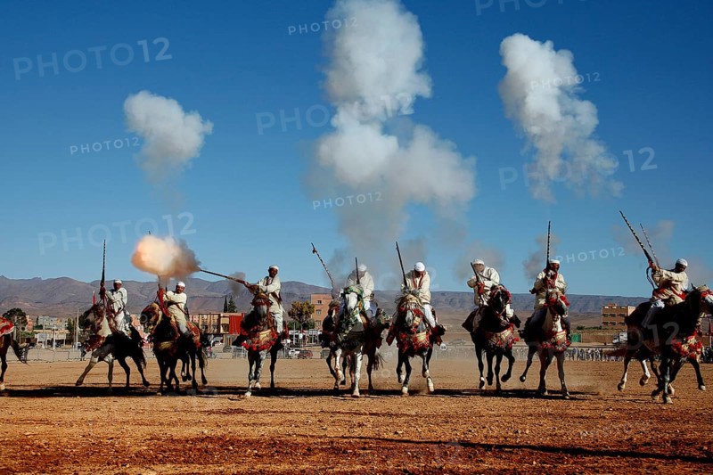 Group of riders fire guns and creates clouds of smoke during a traditional Fantasia ritual, El Kelâa m'Gouna, Morocco