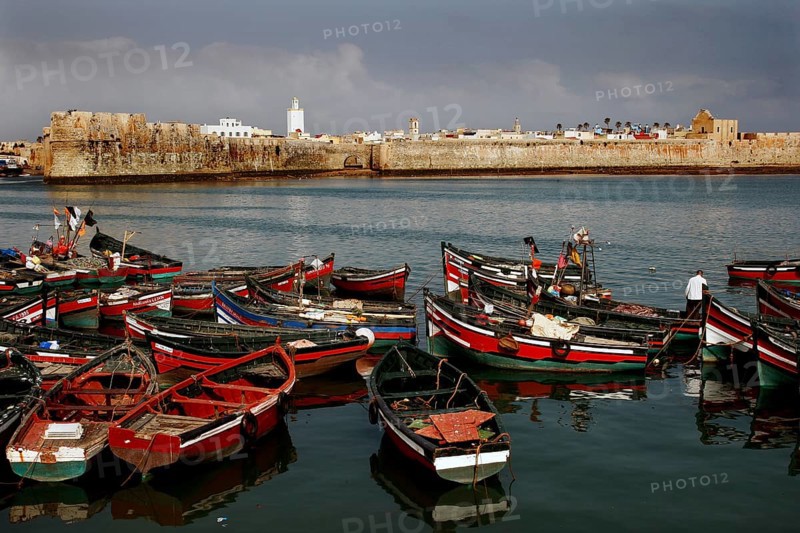View of a medieval fortress from the harbor with lots of red and black boats, El Jadida, harbor, Morocco