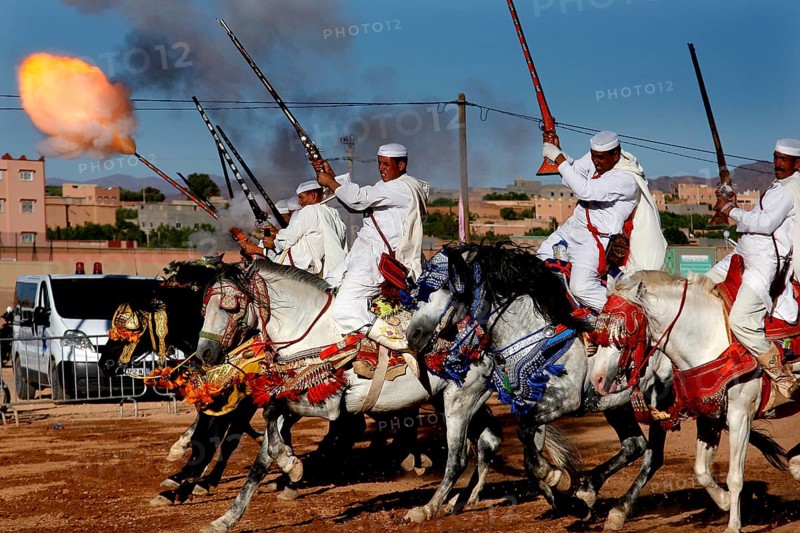 Riding group shoots in sync with rifles and creates fire and smoke in the midst of a traditional backdrop, El Kelâa m'Gouna, Morocco
