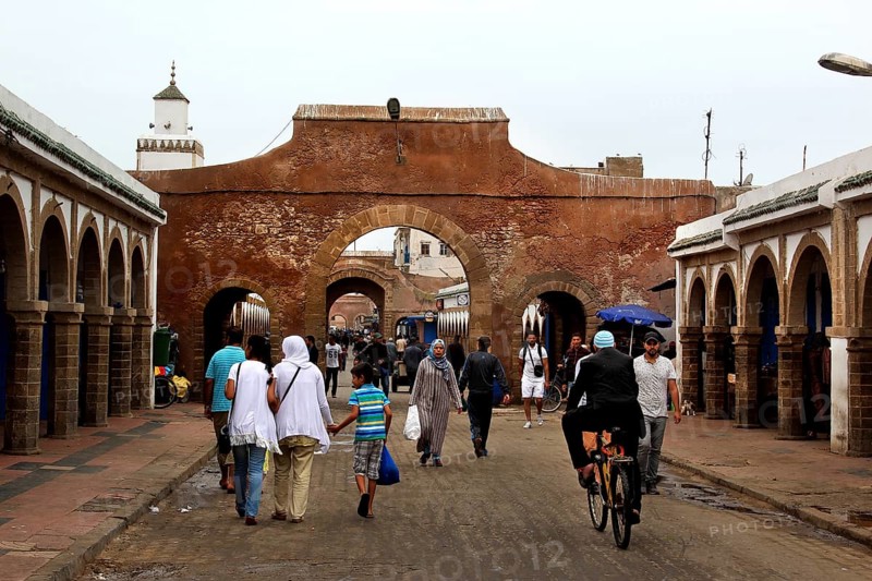People walk through a historic stone gate in the souk of Essaouira, Essaouira, Morocco