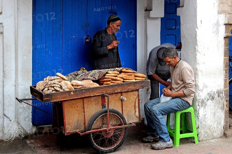 Vendor offers bread from a handcart in Essaouira souk, Essaouira, Morocco