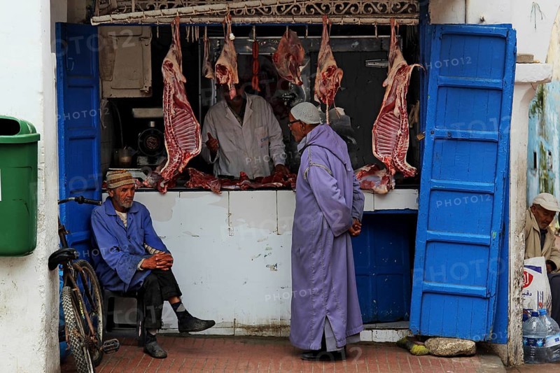 Men stand in front of a butcher shop in the souk of the old town of Essaouira, Essaouira, Morocco