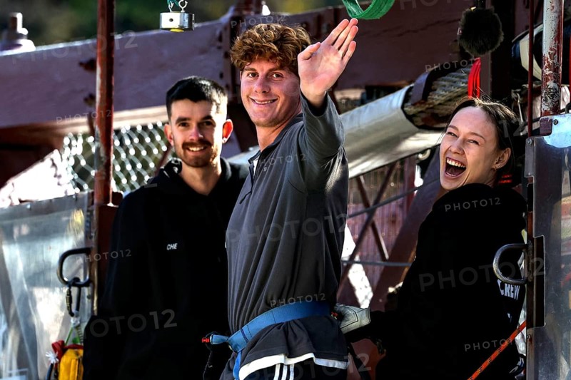 Person in front of bungee jump smiling surrounded by friends at Kawarau Bridge, Queenstown, Kawarau Bridge, New Zealand