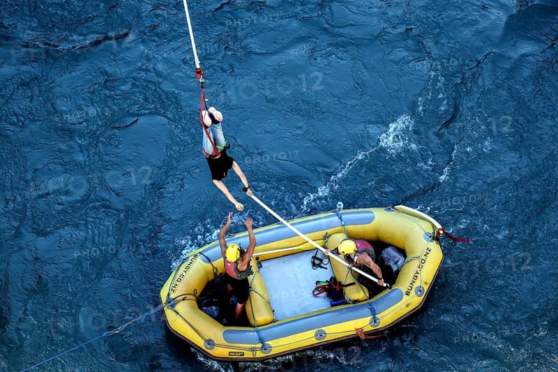 Bungee jumper is stopped over a yellow inflatable boat in the river, Queenstown, Otago, New Zealand