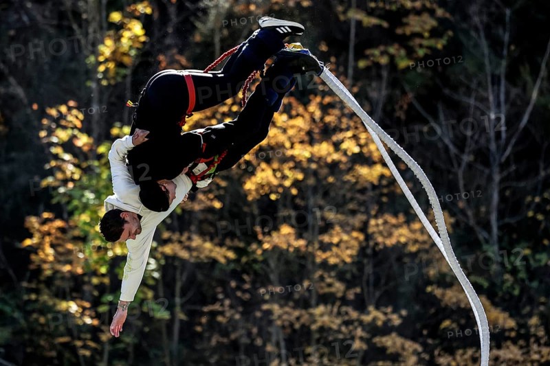Partner bungee jump in spectacular acrobatics against a backdrop of autumn leaves, Queenstown, Otago, New Zealand