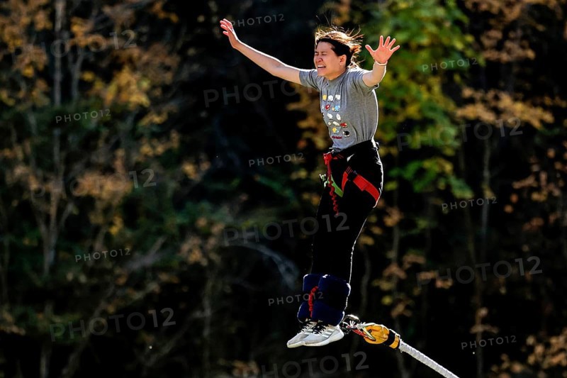 Female bungee jumping off Kawarau Bridge in the midst of autumn forest scenery, Queenstown, Otago, New Zealand