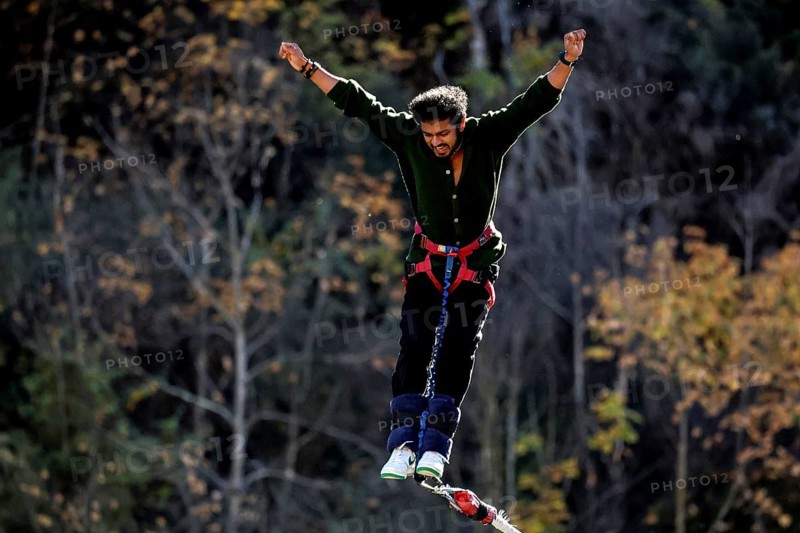 Person with arms spread out bungee jumping in front of autumn landscape, Queenstown, Otago, New Zealand