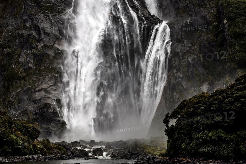Powerful waterfall falls over rocks, creating an impressive spray, Milford Sound, New Zealand