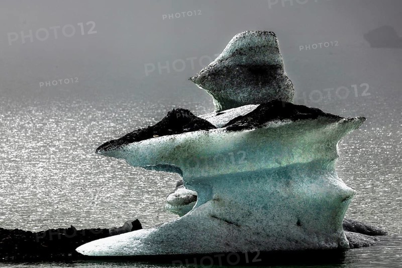 Floating ice formations in shimmering glacial lake under grey sky, Mount Cook, New Zealand