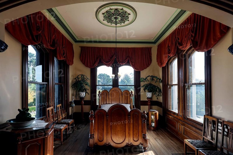 Comfortable bedroom with fine furnishings, large windows and red curtains, Larnach Castle, Otago Peninsula, New Zealand
