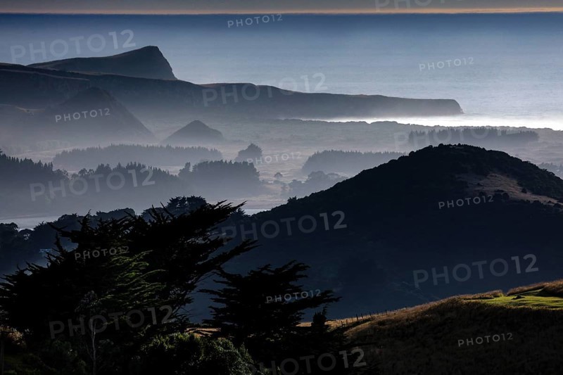 Blurred hills in morning fog along Highcliff Road, Otago Peninsula, New Zealand