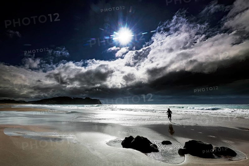Sunny cloudy sky on Hot Water Beach with lonely figure on the beach, Hot Water Beach, Coromandel Peninsula, New Zealand