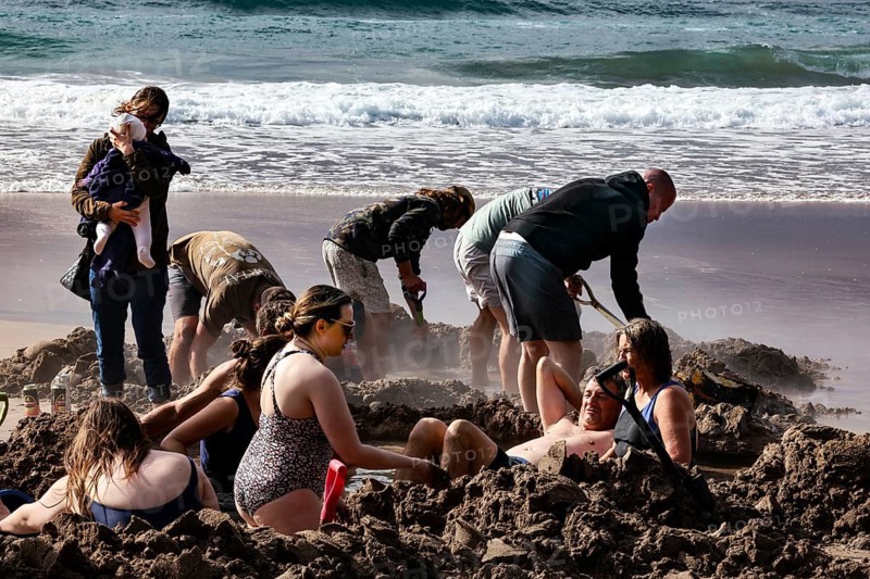 People digging in sand on a beach near the sea, Hot Water Beach, Coromandel Peninsula, New Zealand