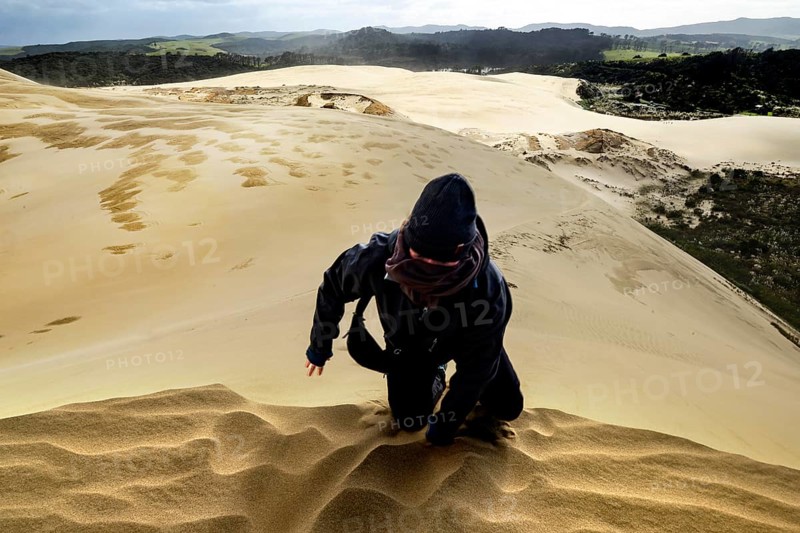 Person fighting his way through sandy dune landscape in stormy weather