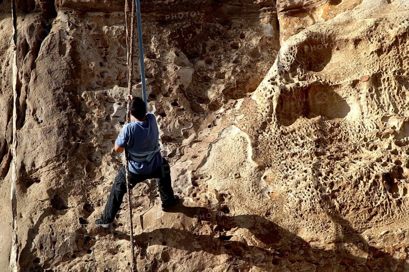 Person climbing a steep rock wall with rope, Debre Damo, Tigray, Ethiopia