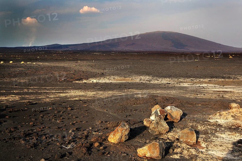 Wide view of the dry, rocky landscape of a lava desert with background mountain