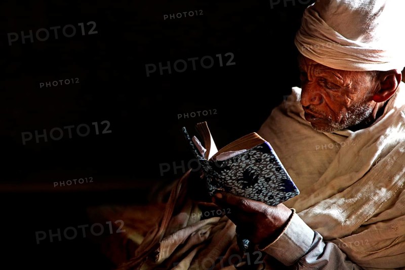 Priest reading in low light at Debre Berhan Selassie church, zero