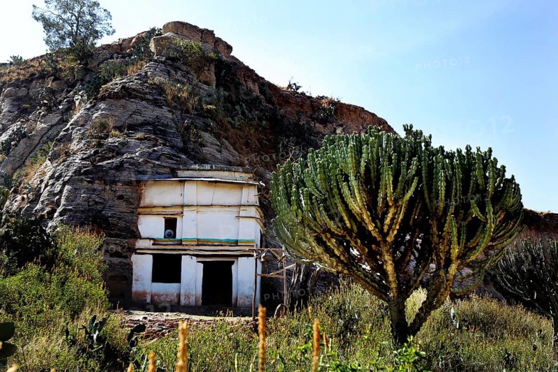 Entrance to Debre Mariam Krokor rock church in front of a steep rock face in natural surroundings, zero